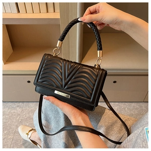 Detail of black quilted leather handbag showing woven handle and gold metal hardware