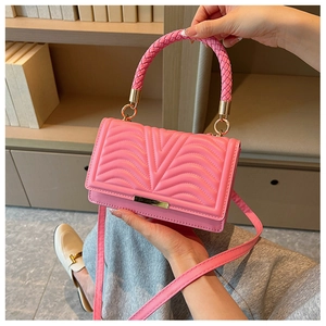 Detail view of pink quilted handbag with gold hardware and thick woven handle