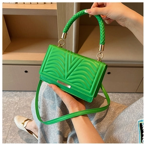 Detail of bright green quilted handbag featuring woven handle and gold hardware