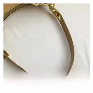 Detailed macro view of beige faux leather strap with crocodile pattern and gold hardware