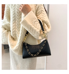 Close-up of black faux crocodile leather shoulder bag with decorative gold chain detail
