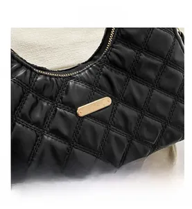 Detail of black quilted shoulder bag with golden metallic hardware and zipper