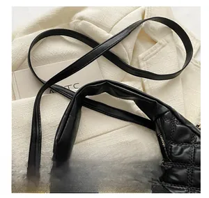 Detail of black quilted leather shoulder bag with adjustable strap and gold hardware