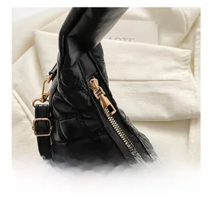 Close-up of golden zipper and quilted black PU leather on a crescent handbag