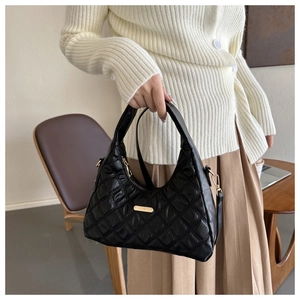 Detail of black quilted puffer bag with gold hardware and removable shoulder strap