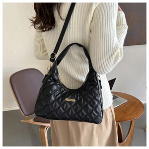 Detail of black quilted crescent bag showing the gold-tone hardware and velvet texture