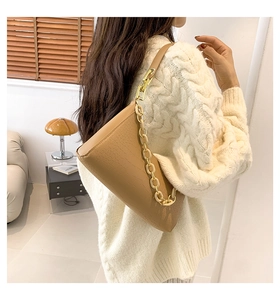 Detail of crocodile embossed leather underarm bag with gold and resin chain straps