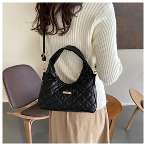 Close-up of black quilted hobo bag featuring diamond stitching and gold metal logo detail