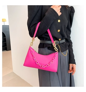 Detail of fuchsia crocodile pattern leather bag with gold and pink chain strap