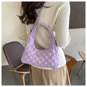 Detail of lilac quilted handbag featuring elegant diamond pattern and golden metal plate