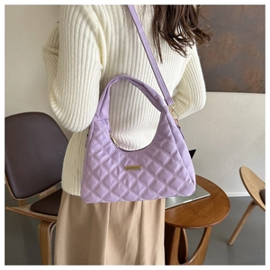 Model wearing lavender quilted shoulder bag with gold hardware and adjustable strap