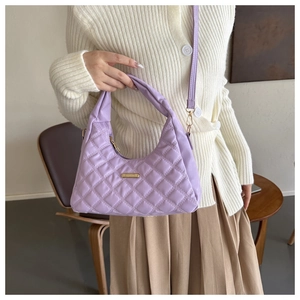 Close-up of lavender quilted handbag with gold hardware on an elegant model