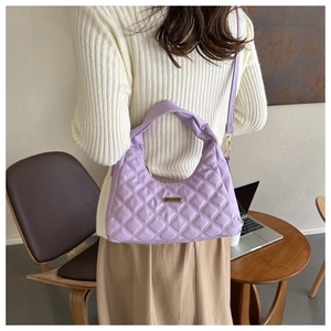 Detail of purple quilted handbag with gold hardware shown in a lifestyle setting