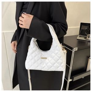 White quilted handbag on black blazer featuring elegant rhombus texture and gold hardware
