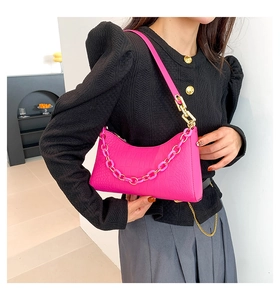 Detailed view of crocodile pattern fuchsia shoulder bag with a chunky chain decoration