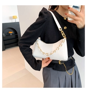 Detail view of white crocodile pattern shoulder bag with resin and gold chain strap