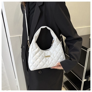 Quilted white PU leather crescent bag with gold hardware shown on a black blazer