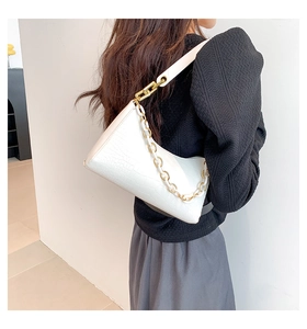Close-up of white crocodile pattern shoulder bag with a gold and white resin chain strap