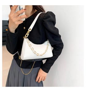Detailed side view of white crocodile pattern shoulder bag with decorative chain on model