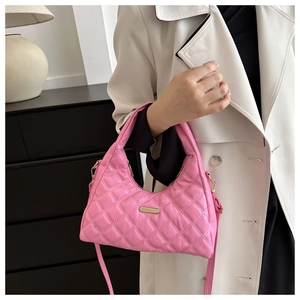 Detailed view of pink quilted handbag with gold hardware and adjustable shoulder strap