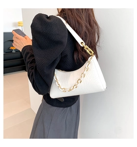 Detail of white crocodile pattern underarm bag featuring gold and white chain strap detail