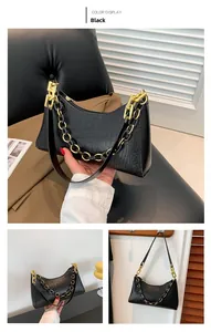 Detail of black crocodile texture bag with gold chain strap and leather handle
