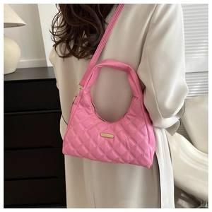 Detail of pink quilted shoulder bag with gold metal logo plate and adjustable strap