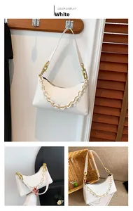 Detailed view of white baguette bag with crocodile pattern and decorative gold chain strap