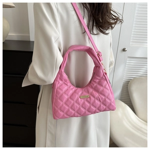 Detailed side view of pink quilted crossbody bag with adjustable strap worn by model