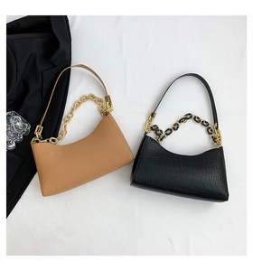 Detail of crocodile pattern leather shoulder bags in beige and black with gold chain straps