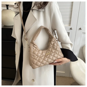 Close-up of beige quilted hobo bag featuring gold logo plate and detachable shoulder strap