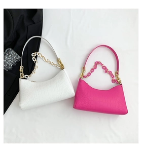 Flat lay of crocodile pattern underarm bags in white and rose pink with chain details