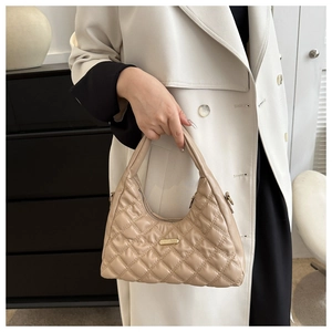 Close-up of beige quilted rhombic texture on a crescent shoulder bag with gold hardware