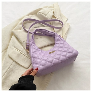 Detail of purple quilted handbag with diamond pattern and gold hardware on blazer