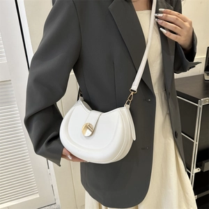 White semi-circular saddle bag with gold metal buckle worn with a grey blazer