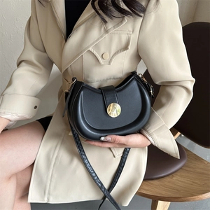 Minimalist black crescent shoulder bag with golden round buckle and adjustable strap