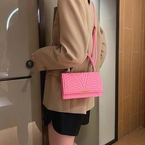 Pink quilted crossbody bag with woven handle and gold metal trim worn by a model