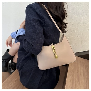 Detail of a chic beige underarm bag featuring a metallic gold lock and retro smooth leather