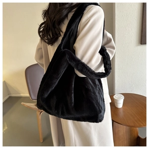 Détail d'un grand sac cabas en peluche noire porté à l'épaule dans un café confortable