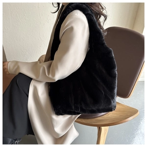 Détail d'un grand sac cabas en peluche noire porté par un mannequin en intérieur