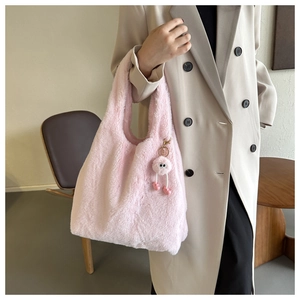 Détail d'un sac cabas en peluche rose clair avec un pompon duveteux et une texture douce