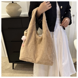 Détail d'un grand sac cabas beige en peluche avec un adorable charme rose à l'avant
