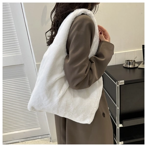 Détail d'un grand sac cabas en peluche blanche porté sur un manteau marron