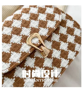 Close-up of houndstooth plaid fabric texture and gold U-shaped metal buckle on saddle bag