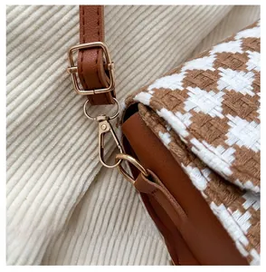 Macro detail of gold hardware hook and houndstooth texture on vintage saddle bag