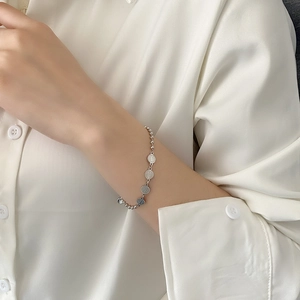 Bracelet à perles argentées avec charmes chinois gravés porté au poignet de femme