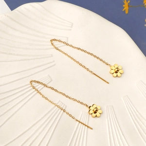 Elegante goldene Gänseblümchen-Ohrketten auf weißem Keramikteller mit floraler Deko