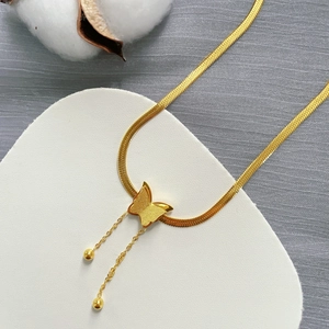 Collana con farfalla e nappa in acciaio al titanio dorato su espositore bianco a cuore