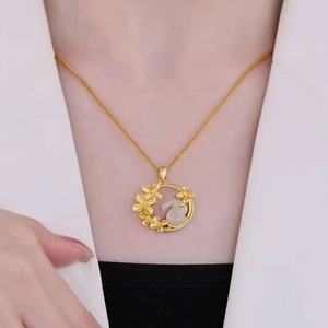 Elegant gold rabbit necklace with floral pendant worn by model on black and white background