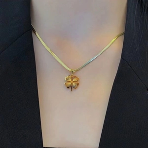 Gold plated four leaf clover pendant on flat snake chain necklace worn by a fashion model